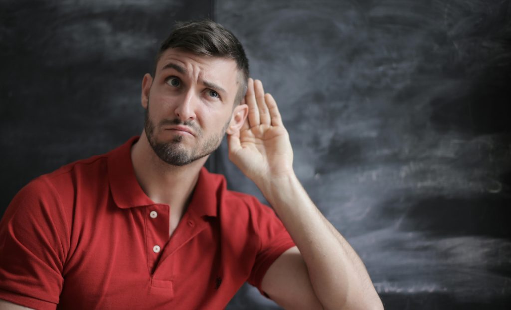 A man cupping his ear to improve his hearing.